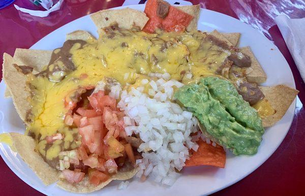 Bean and cheese nachos with tomato, onion and guacamole added.