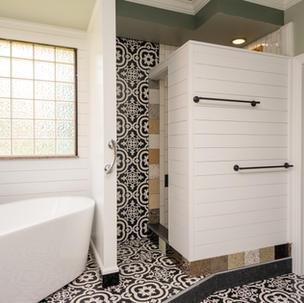 White subway tiles adorn  the space  of the primary bathroom,  with a deep soaker tub as its center.