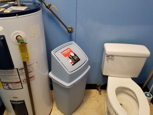 Water heater next to trash can and toilet. Nasty floor.