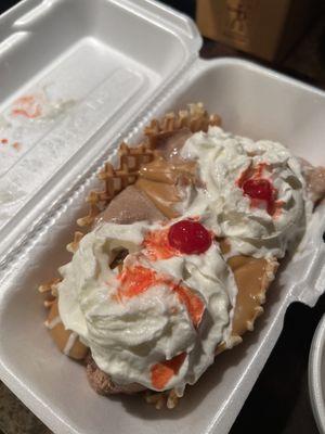 Waffle taco with chocolate PB, PB sauce, whipped cream, and a cherry.