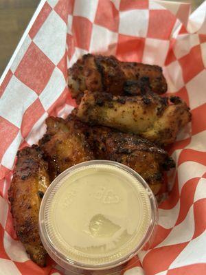 Half batch of buffalo wings with a side of blue cheese