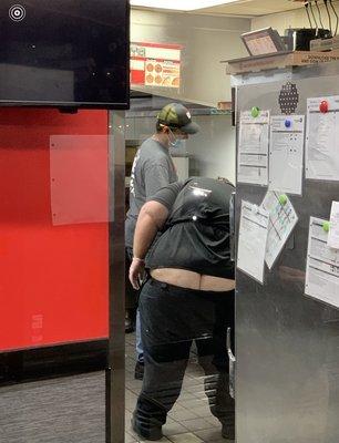 Employees preparing pizza in Kitchen.