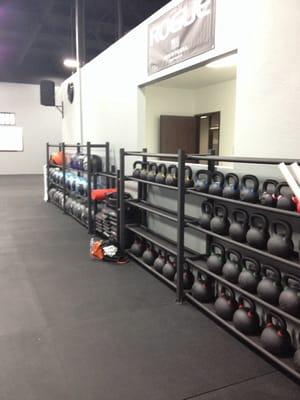 Wall balls, ab mats, and kettle bells lined up against the wall.