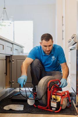 Technician is working on clearing a blockage in the kitchen sink drain