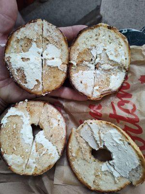 Two bagels with not enough cream cheese for even a half bagel.