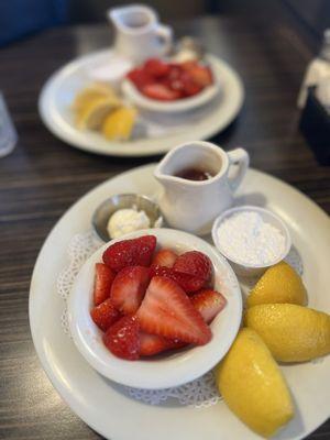 The toppings: fresh lemon, whipped butter, strawberries, powdered sugar, and strawberry syrup