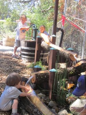 Happy kiddos pumping water down the log sluiceway in the "rnature experience" area of the Grace playground.