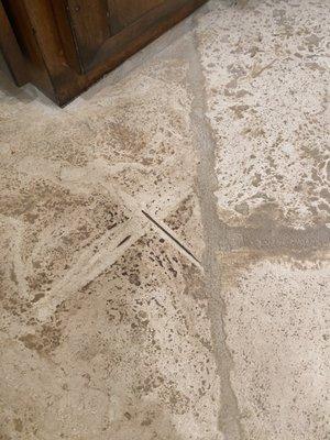 A X etched into my travertine in attempt to erase the X they penciled and sealed into it.