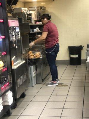 Photo of employee breaking health regulations by placing fresh crossiant on a dirty garbage pale.