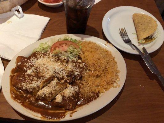 This a plate of Chicken Enchiladas Poblanas with a side of rice & a crunchy beef taco.