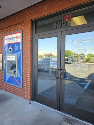 The main entrance to the Freedom First Credit Union Crossroads branch and its modern ATM machine outside.