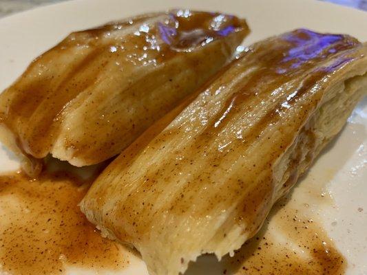 Two red pork tamales with a little hot sauce on them from the weekly Saturday fundraiser.  Very good.