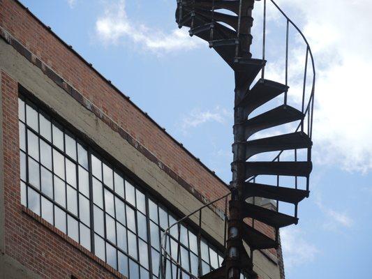 Spiral fire escape sculpture titled Architectural DNA between buildings