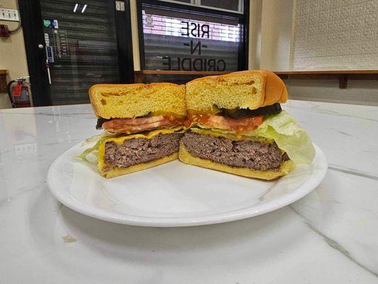 Cheeseburger with pickles, lettuce, and tomatoes on a brioche bun