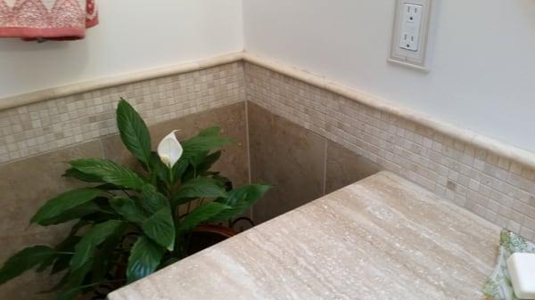 Porcelain tile from floor up wall to travertine wainscoting accent tiles that pair perfectly with travertine top on vanity.