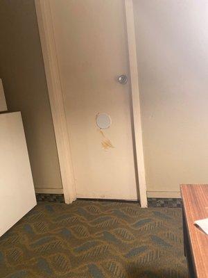 Disgusting smudge on bathroom door with a hole being covered