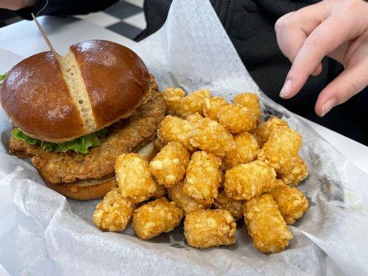 Pork tenderloin on a pretzel bun with tater tots.