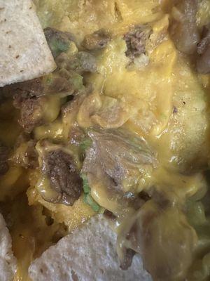 Gas station cheese, three slices of avocado and some grainy beef over chip crumbs (nachos)