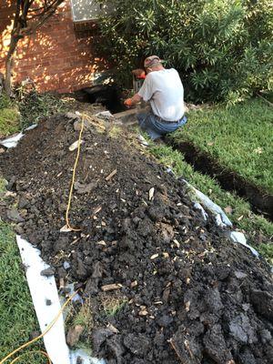 Lee using chipping hammer to go through garden beam for French drain.