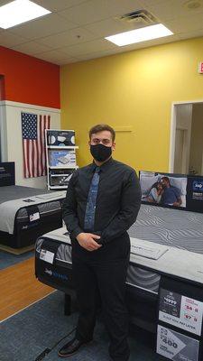 Jared Swindon in front of a Sealy Hybrid Mattress and adjustable base.