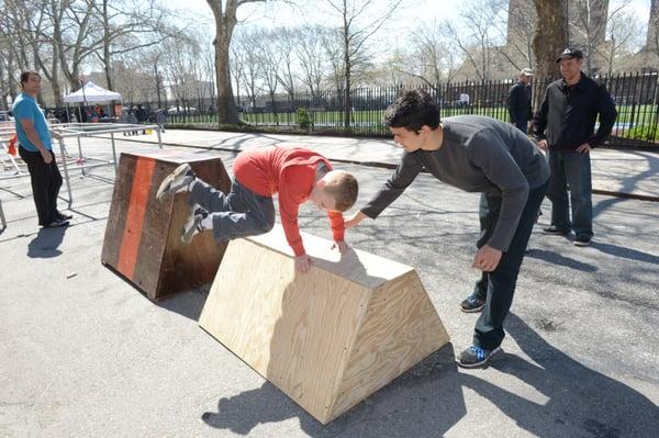 Instructor Scott Sublett Olsen gives a young boy tips for refining his vault at the annual Harlem Street Games