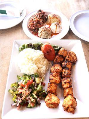 This image showcases a beautifully presented Turkish chicken kebab platter. The dish features succulent, perfectly grilled chicken skewers s