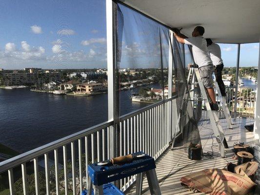 The team re-screening an existing balcony screen enclosure.