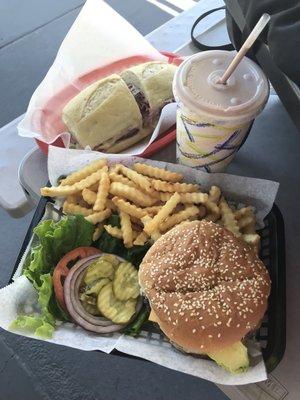 Pastrami sandwich in back and in front a chocolate milkshake, krinkle fries and a Avochee Burger