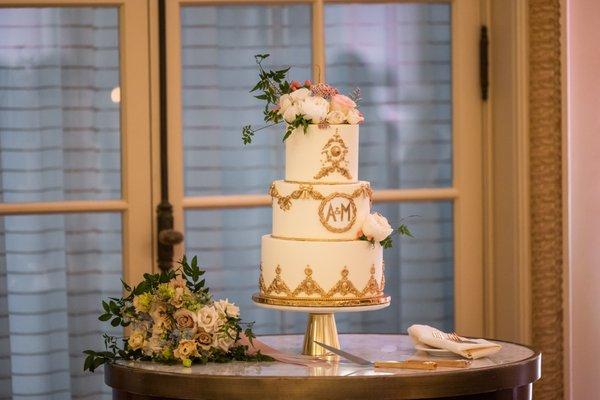 3 tiered wedding cake with smooth buttercream, gilded gold pieces and fresh florals at the Westgate Hotel