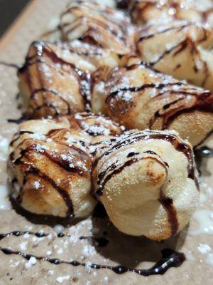 Close up of Knaughty Knots - Sweet Ricotta, Vanilla Icing & Chocolate Sauce Drizzle, Powdered Sugar Sprinkle 9.4.22