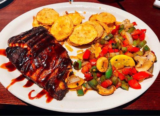 Grilled salmon with sriracha bourbon sauce, sautéed vegetables, and fried squash.