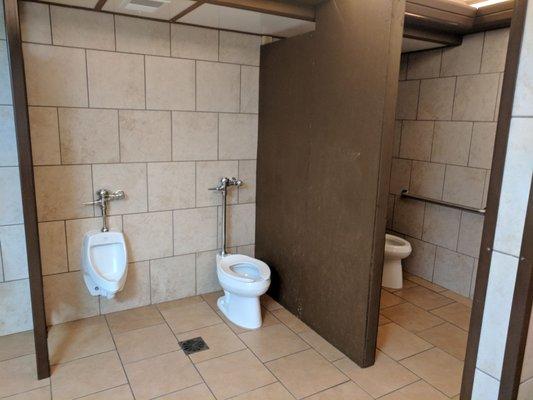 Men's bathroom sit down toilet stalls