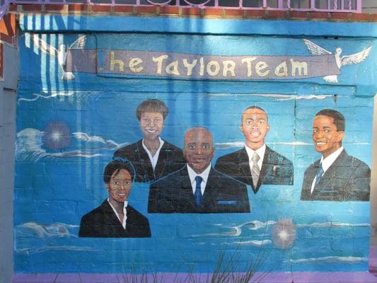 the front wall of the house shows a mural of the Taylor Team