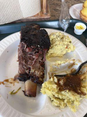 Beef rib with potato salad and mashed potatoes with brown gravy.