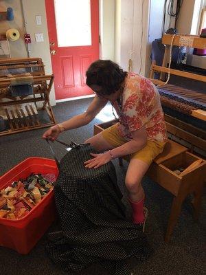 An artist cutting strips to be used onthe loom to make a rag rug.