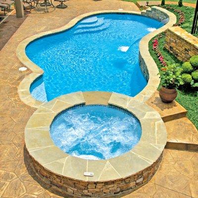 Concrete (gunite/shotcrete) pool with elevated spa, raised bond-beam (wall), and twin cascade water features