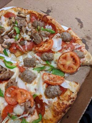 Pizza with tomatoes (on one half, mushrooms on the other), sausage, pepperoni, onions, and green pepper.