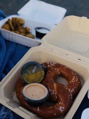 Baked pretzel with honey mustard and jalapeño cheese dipping sauce and fried pickles in the back