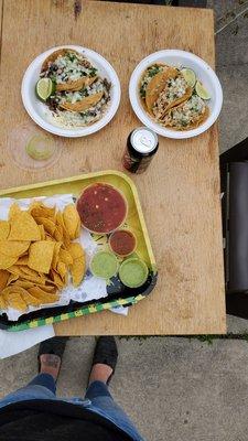 Beef and cheese tacos, chicken tacos, chips and variety of sauces. They are on a wooden table photographed from above.