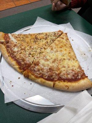 Two plain slices. Left is covered with garlic, crushed red peppers, and oregano. The right is a plain cheese slice.