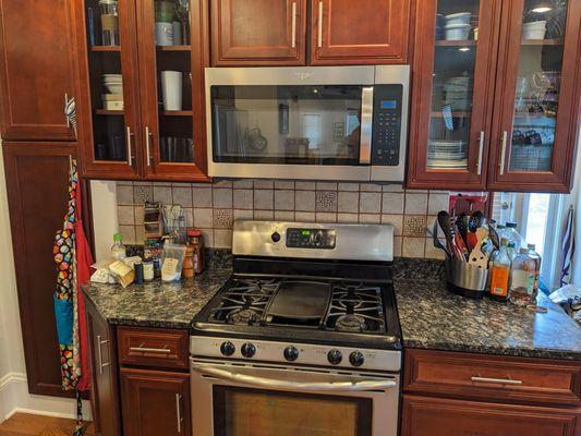 New microwave installed between wood-panel shelves