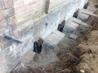 Foundation settling repair with concrete piers and steel brackets installed.