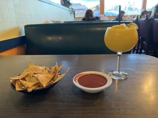 Small bowl of chips with a red chile salsa and a Mango Margarita