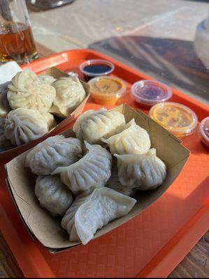 Steamed Chicken Momo in the front and Steamed Pork Momo in the back with an assortment of sauces