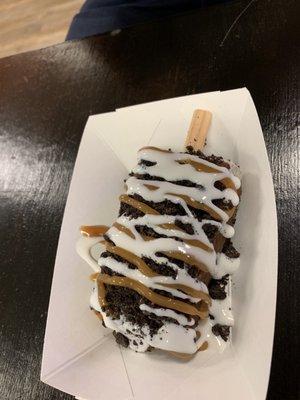 Paleta dipped in chocolate and covered in caramel and Oreo crumbs