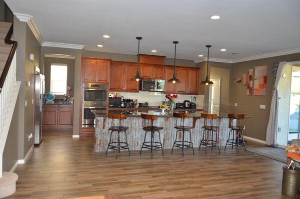 Albert did custom metalwork under kitchen island, three hanging lights, crown molding, paint, and staining of arm for stairs on left