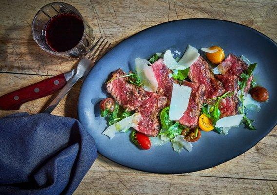 NY Strip Steak Tagliata with arugula, mostocotto, olio fresco, and parmesan