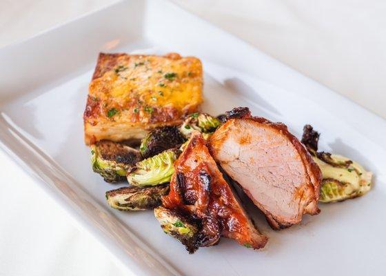 Bacon-wrapped pork tenderloin, Brussels sprouts, three-cheese gratin, and our house-made BBQ sauce