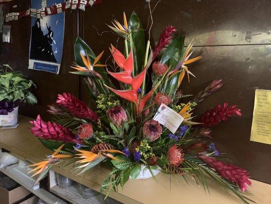 Tropical mix Of Heliconia, bird of paradise, ginger, pincushion, pink mink & safari sunset proteas with assorted foliage & fillers.