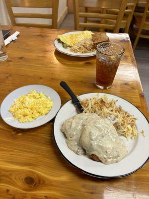 Chicken fried chicken with hash browns and scrambled eggs, and an omelette with hash browns and toast